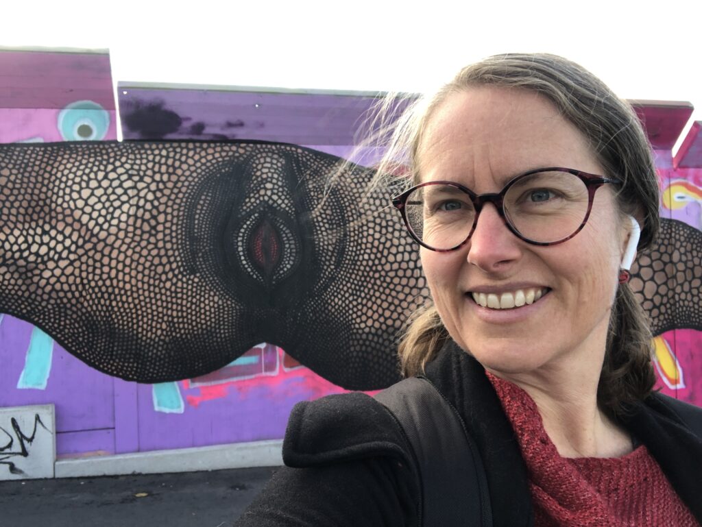 Me in front of street art titled ‘God giving a fuck’ by Carolina Falkholt, on barricades covering road works between Nordstan, a big shopping center in the center of Gothenburg, and the Opera.